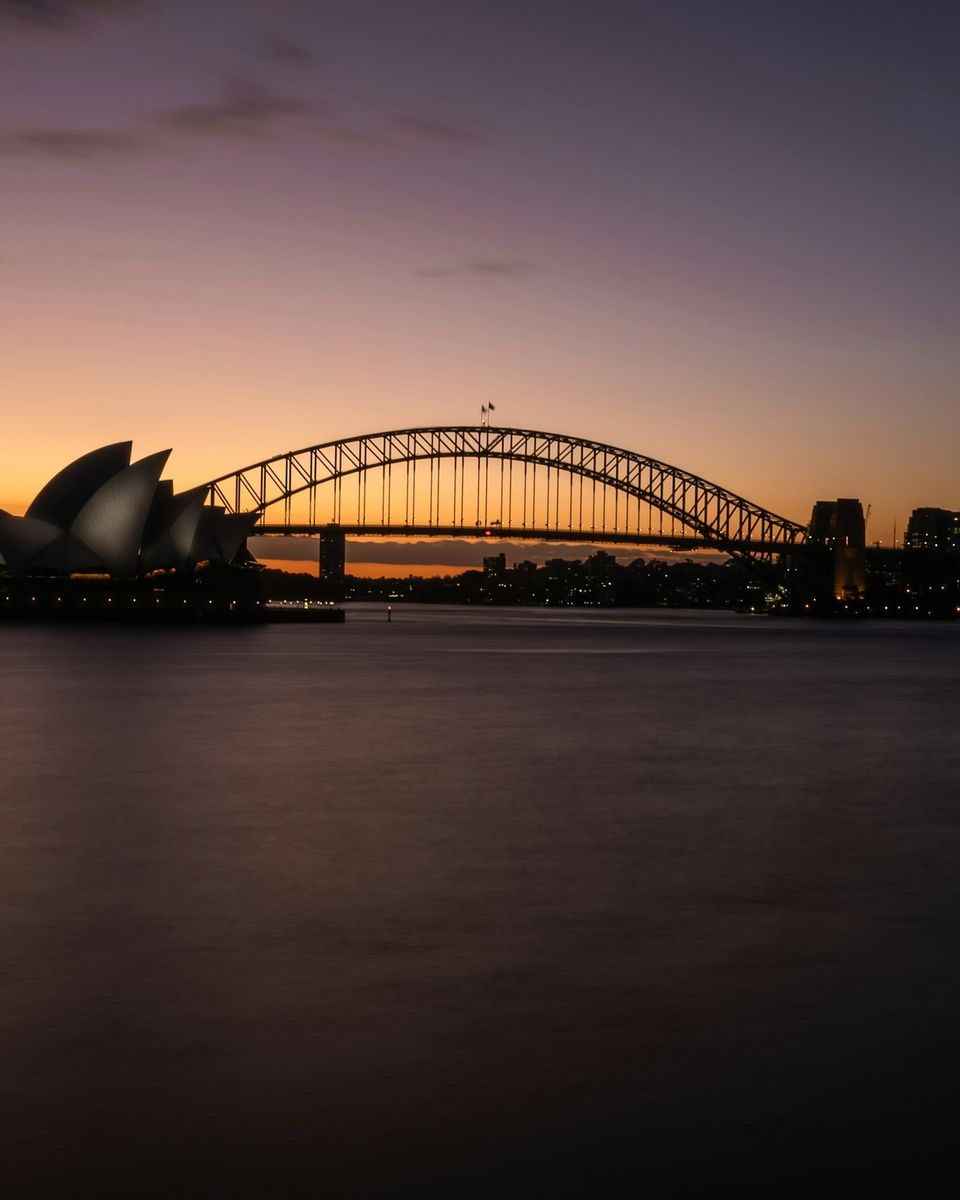 Sydney Opera House and Harbour Bridge at dusk reflected in calm harbour water