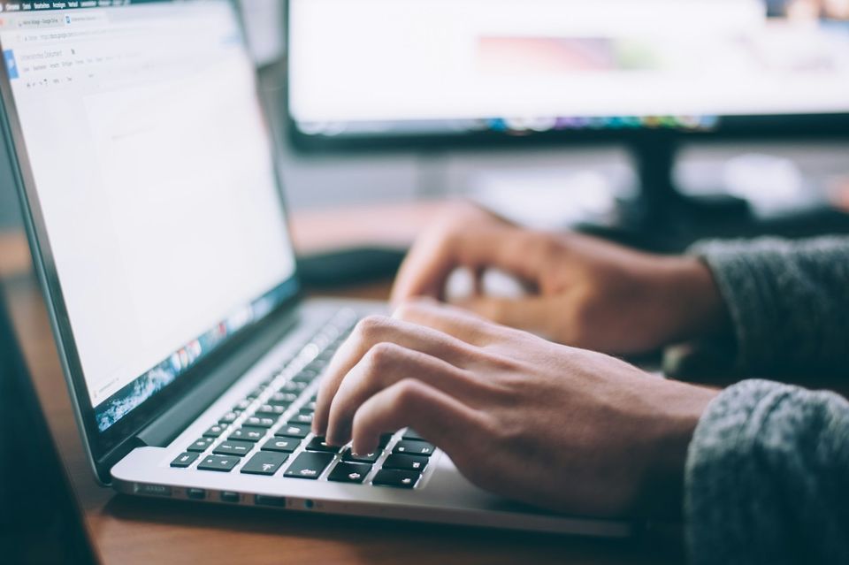Hands typing on a laptop in a quiet workspace